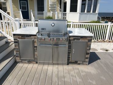 Outdoor grill center with granite top and two stainless steel doors.