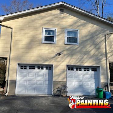 Two-car garage with cream-colored walls and white doors under a clear blue sky.