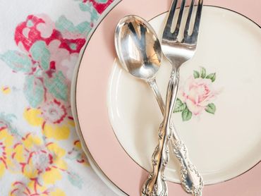 Floral dessert plate with a fork and spoon set on a colorful vintage tablecloth