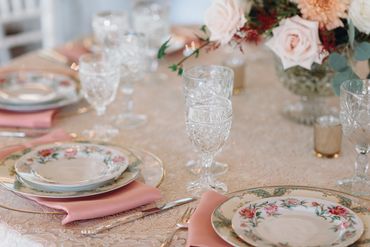 Banquet table set with mismatched floral china, glassware and silverware.