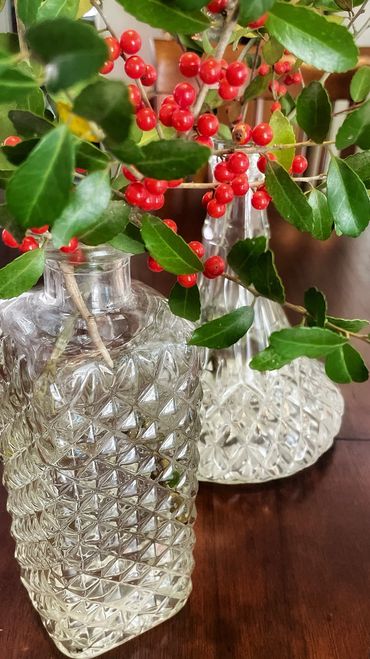 Holly stems in a pair of vintage decanters as holiday decor