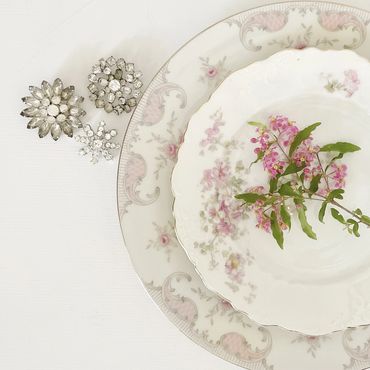Vintage floral patterned plates adorned with fresh flowers and vintage rhinestone jewelry