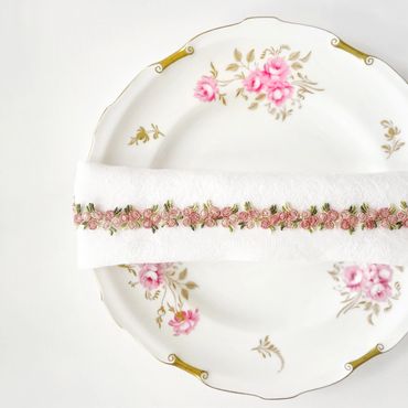 Floral dinner plate with a napkin wrapped across the top and a floral ribbon embellishment.