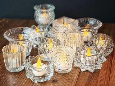 Assorted vintage crystal votive candle holders glowing with candlelight.