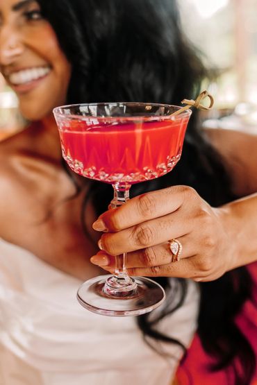 Bride holding a cocktail in a vintage champagne coupe at a wedding