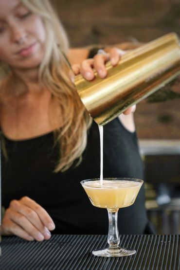 Bartender pouring a mocktail into a vintage goblet at an engagement party