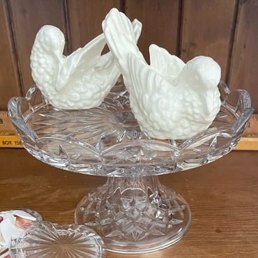 Vintage porcelain doves arranged on a crystal pedestal plate for buffet table decor at a wedding