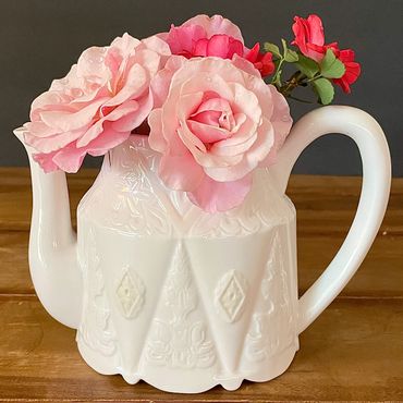 Garden roses in a vintage teapot, used as a vase