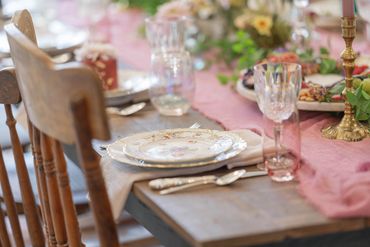 Dining table set with china, crystal goblets, flowers, candle holders and silverware.