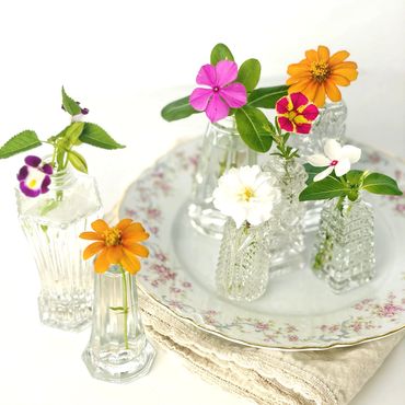 Assorted crystal salt shakers doubling as mini vases holding snips of garden blossoms.