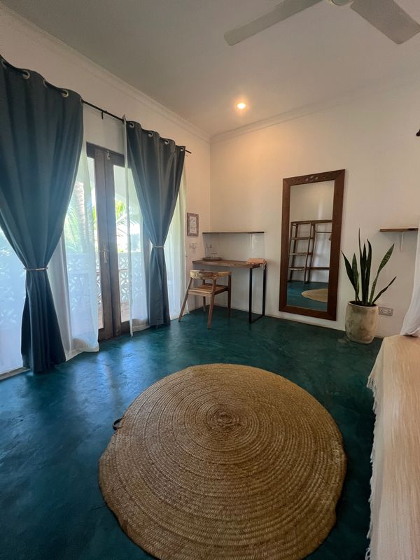 Minimalist room with teal floor and round woven rug