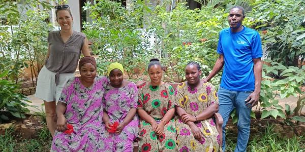 Group of people posing outdoors among plants.