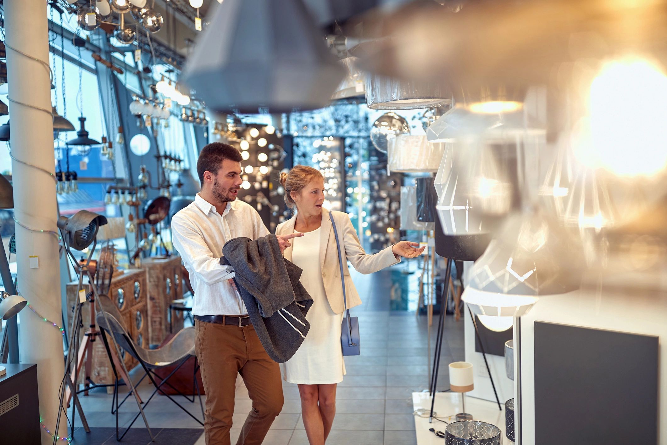 A young couple shopping for lighting fixtures in a modern showroom.