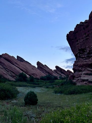 Rock formations and greenery under a clear blue sky at dusk.