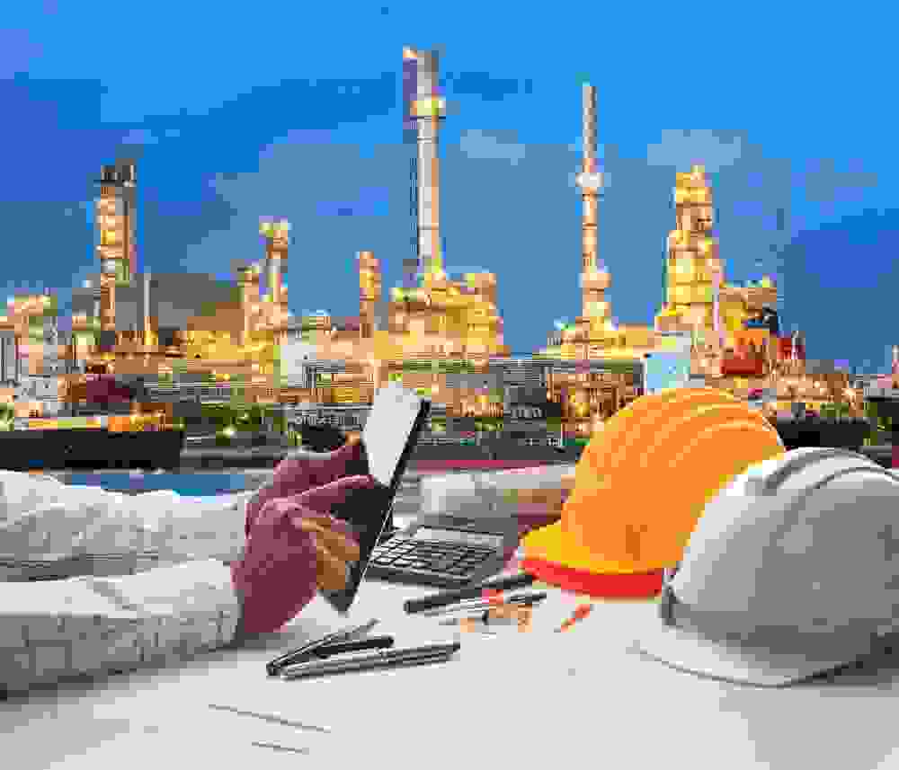 engineering working on computer tablet against beautiful oil refinery background