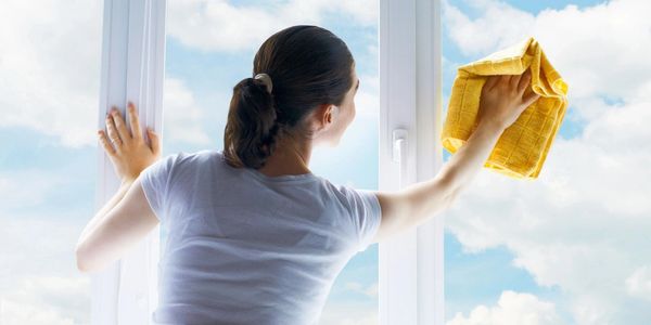 Woman cleaning window glass with a cloth 