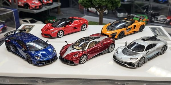 Five detailed miniature sports cars displayed on a white platform.