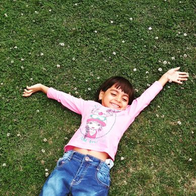 Happy child stretched out on grass, after getting a full night's sleep after sleep training