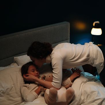 Mother putting child back in bed after waking up in the middle of the night