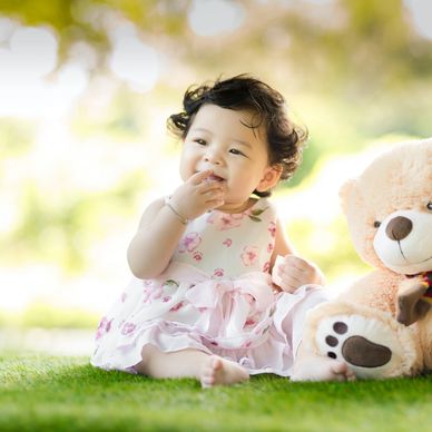 Joyful baby with a teddy bear enjoying outdoor play in a park, energized after a good nap.