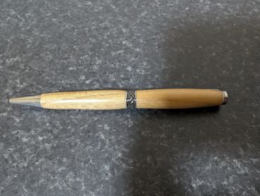 Wooden pen with metal accents on a dark surface.