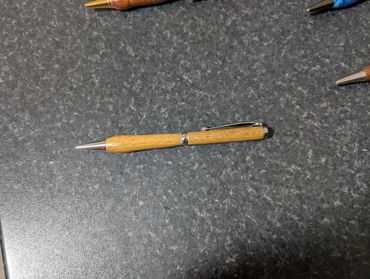 A wooden pen with metallic details on a dark textured surface.