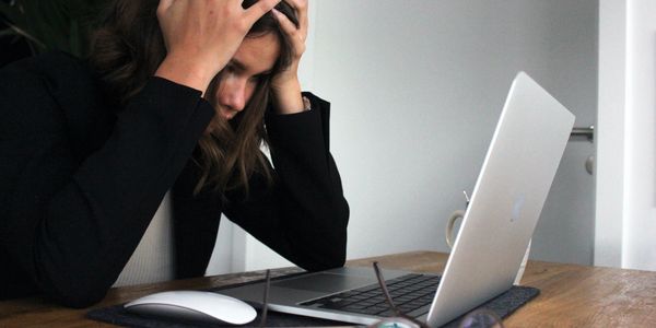 Stressed out woman sitting at a desk looking at a laptop computer