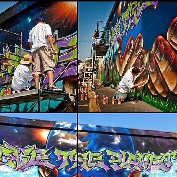Artists creating vibrant graffiti murals on a large outdoor wall.