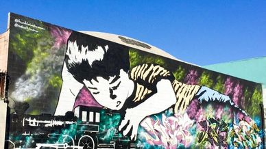 Large mural of a child looking at a toy train.