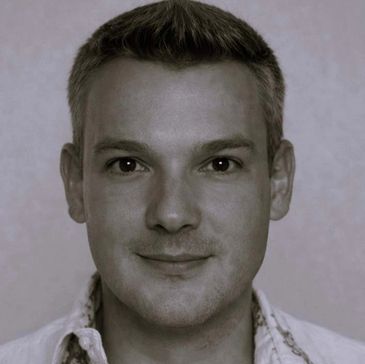 Close-up portrait of a smiling man with short hair.