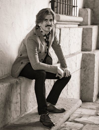 Man with mustache sitting on stone bench in vintage style.