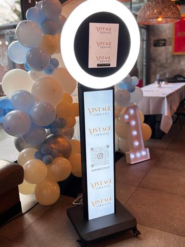 Photo booth with ring light and balloon decoration at an event venue.