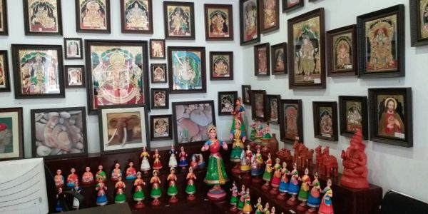 A collection of traditional Indian paintings and clay figurines displayed on walls and tables.