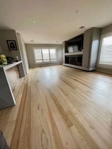 Spacious living room with light wood flooring and large windows.
