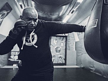 Boxer practicing a punch on a heavy bag in a gym.