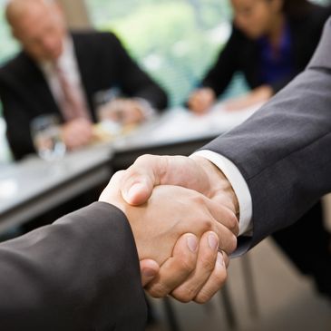 Two people shaking hands in a business setting.