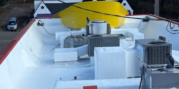 View of a rooftop with HVAC units and a large statue facing away, wearing a blue shirt.