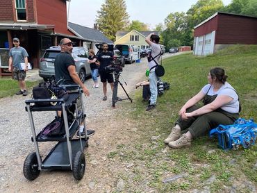 Photo of the filming of "Dream Devil". A group of filmmakers sit and smile to one another.