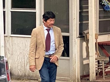 Photo of the filming of "Dream Devil". A man stands on the porch of a house at Houser's Crossing