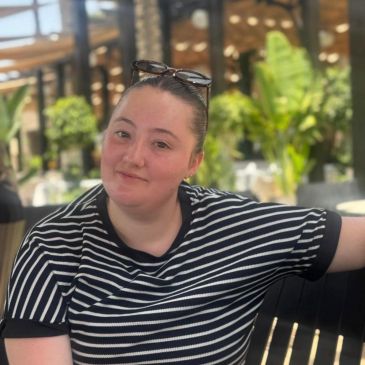 Woman in a black and white striped shirt sitting outdoors.