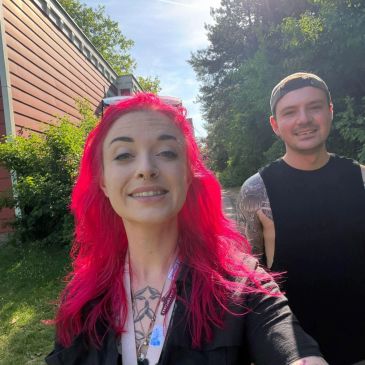 Two smiling people outdoors on a sunny day.