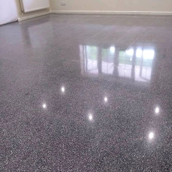 Highly polished speckled gray floor reflecting lights and window.