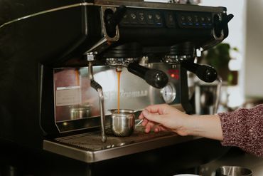 Close-up of an espresso machine brewing coffee into a metal cup.