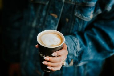 Person holding a cup of coffee with latte art.