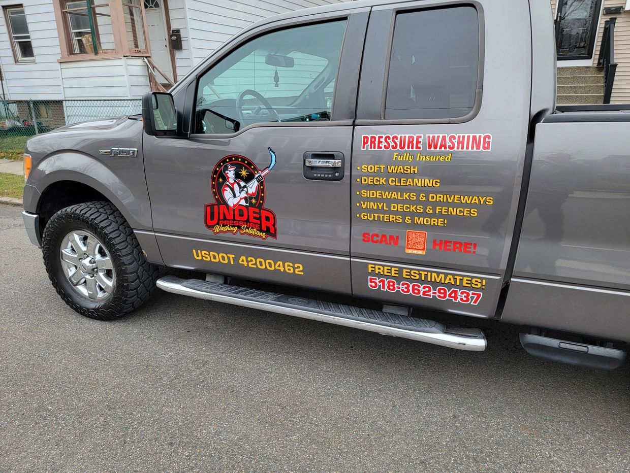 An Under Pressure Washing Sollutions fleet truck with branding and contact info.