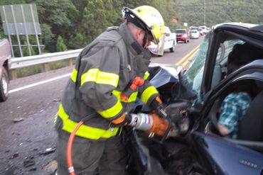 Fireman helping a person stuck in a vehicle