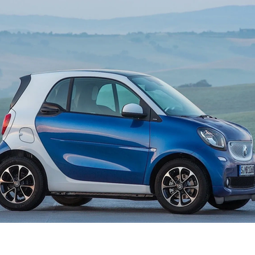 Compact blue and white Smart car parked outdoors with scenic hills in the background.