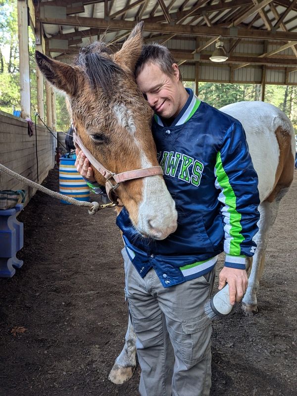 A man affectionately hugging a horse.