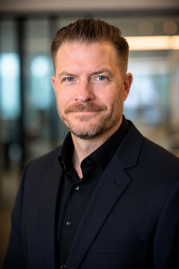 Professional man in a dark suit smiling confidently.