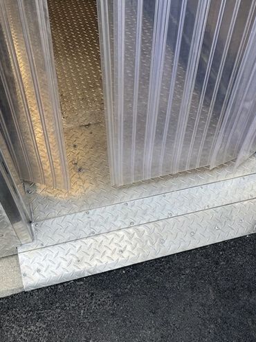 A close-up, ground-level view of a custom-engineered commercial walk-in freezer threshold assembly.